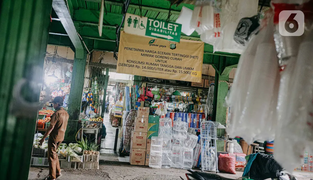 Pedagang melintas di dekat spanduk terkait penetapan harga minyak goreng subsidi di lorong Pasar Kramat Jati, Jakarta, Senin (30/5/2022). Adanya spanduk minyak goreng subsidi tersebut  untuk mensosialisasikan soalnya Per 31 Mei 2022 pemerintah berencana mencabut subsidi minyak goreng curah. (Liputan6.com/Faizal Fanani)