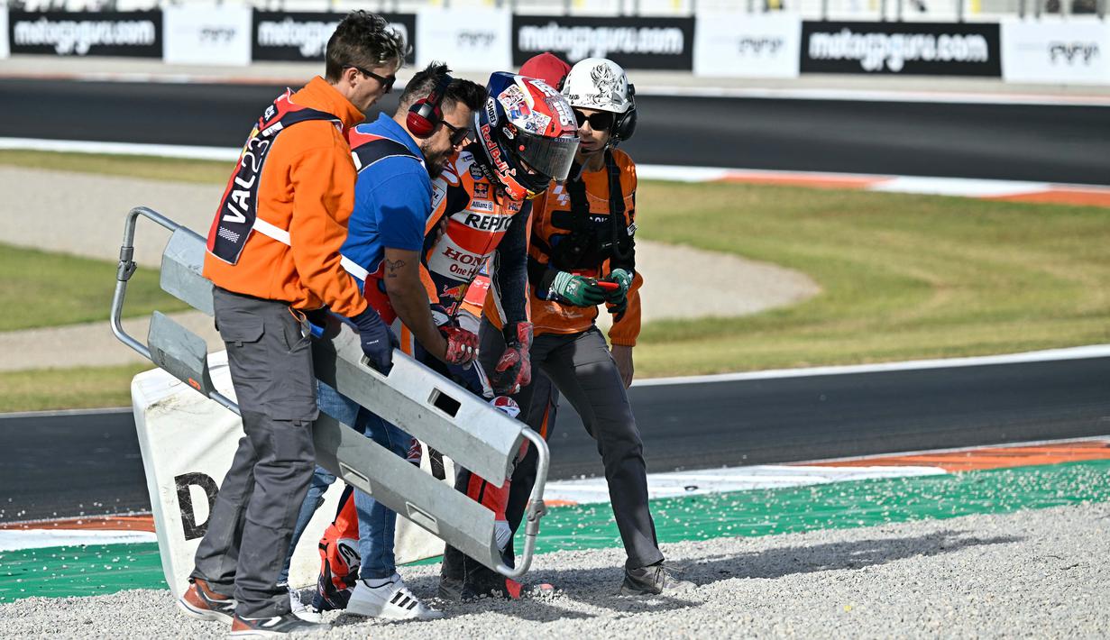 Pembalap Repsol Honda, Marc Marquez (tengah) mendapatkan bantuan tim medis setelah bersenggolan dengan pembalap Pramac Racing, Jorge Martin dalam MotoGP Valencia yang berlangsung di Sirkuit Ricardo Tormo, Valencia, Spanyol Minggu (26/11/2023). (AFP/Javier Soriano)