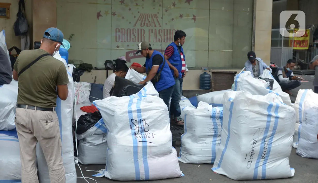 Sejumlah porter mengemas pakaian jadi ke dalam karung di Kawasan Tanah Abang, Jakarta, Senin (11/10/2021). Menurunnya level PPKM jakarta menjadi level 3 membawa berkah bagi para kuli panggung dikarenakan geliat pasar tersebut kembali berjalan. (Liputan6.com/Angga Yuniar)