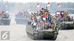 Warga membawa bendera merah putih saat menaiki tank TNI menyaksikan HUT TNI ke-70 di Dermaga Indah Kiat, Cilegon, Banten, Senin (5/10/2015). HUT TNI Ke-70 ditandai atraksi tempur tiga matra TNI Angkata Darat, Laut dan Udara. (Liputan6.com/Faisal Fanani)