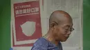 Seorang pria berjalan di dekat koran yang menampilkan iklan yang menyarankan orang untuk memakai masker, di sebuah kios di Beijing pada Senin, 23 Mei 2022. Beijing memperpanjang perintah bagi pekerja dan siswa untuk tinggal di rumah dan memerintahkan pengujian massal tambahan pada hari Senin untuk membendung kasus COVID-19 yang kembali meningkat di ibu kota China. (AP Photo/Andy Wong)