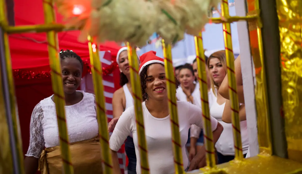 Narapidana perempuan tersenyum di balik jeruji penjara yang dihias dengan dekorasi Natal di Penjara Nelson Hungria, Rio de Janeiro, Kamis (13/12). Penjara ini mengadakan kompetisi menghias sel menggunakan dekorasi bernuansa natal. (AP/Silvia Izquierdo)