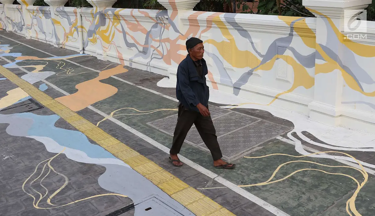 Warga melintas di depan Kampung Tematik Sketsa di kawasan Penjaringan, Jakarta Utara, Rabu (1/7). Sketsa-sketsa yang menghiasi kawasan tersebut dibuat dalam rangka menyambut Asian Games XVIII Tahun 2018. (Liputan6.com/Immanuel Antonius)