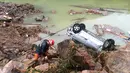 Seorang petugas berada di sebelah mobil yang terbalik di lokasi tanah longsor yang disebabkan oleh hujan deras yang dibawa oleh Topan Megi, di Sucun Village, Lishui, provinsi Zhejiang, Tiongkok, (29/9). (REUTERS/Stringer)