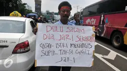 Seorang Supir Taksi membawa spanduk saat demo di depan Gedung DPR/MPR, Jakarta, Selasa (22/3/2016). Selain melakukan demo, supir taksi tersebut melakukan sweeping ke supir taksi yang beroperasi di dalam tol dan membakar ban. (Liputan6.com/Johan Tallo)