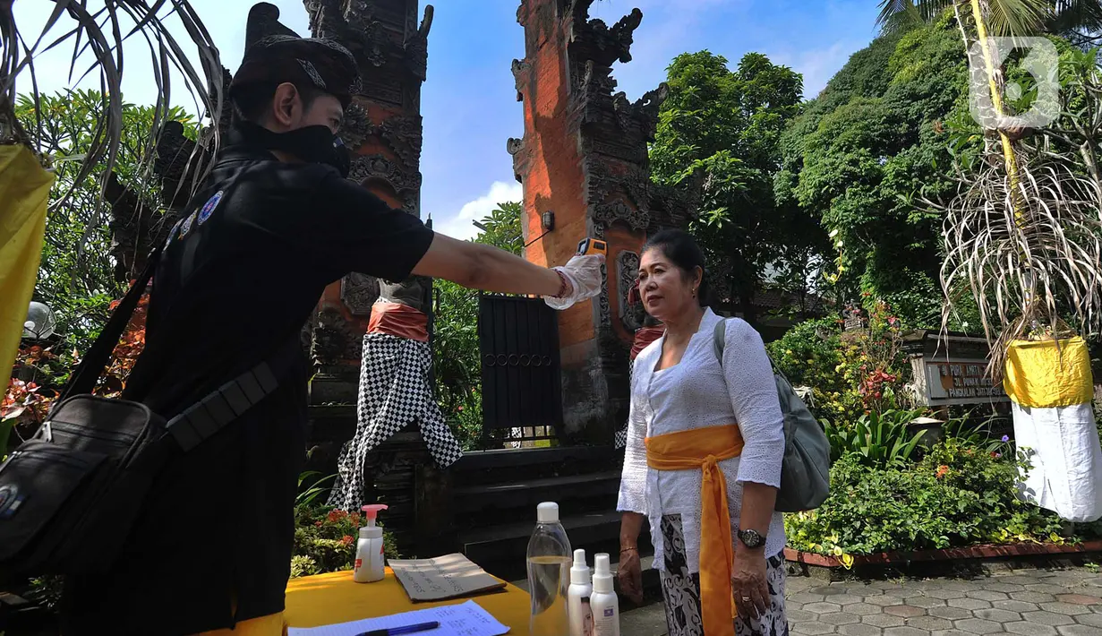 Petugas memeriksa suhu tubuh pengurus Pura Amerta Jati menjelang persiapan Hari Raya Nyepi Saka 1942 di Cinere, Depok, Selasa (24/3/2020). Rangkaian perayaan Nyepi di sejumlah pura hanya akan dilakukan oleh panitia dalam jumlah terbatas untuk mencegah penyebaran Covid-19. (merdeka.com/Arie Basuki)