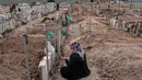 Seorang wanita berduka di depan nisan di sebuah pemakaman di distrik Adiyaman, Turki, Minggu (19/2/2023). 108 jiwa meninggal dan 170 rumah ambruk di Desa Yaylakonak distrik Adiyaman, Turki akibat gempa berkekuatan 7,8 magnitudo yang terjadi pada 6 Februari lalu. (BULENT KILIC/AFP)