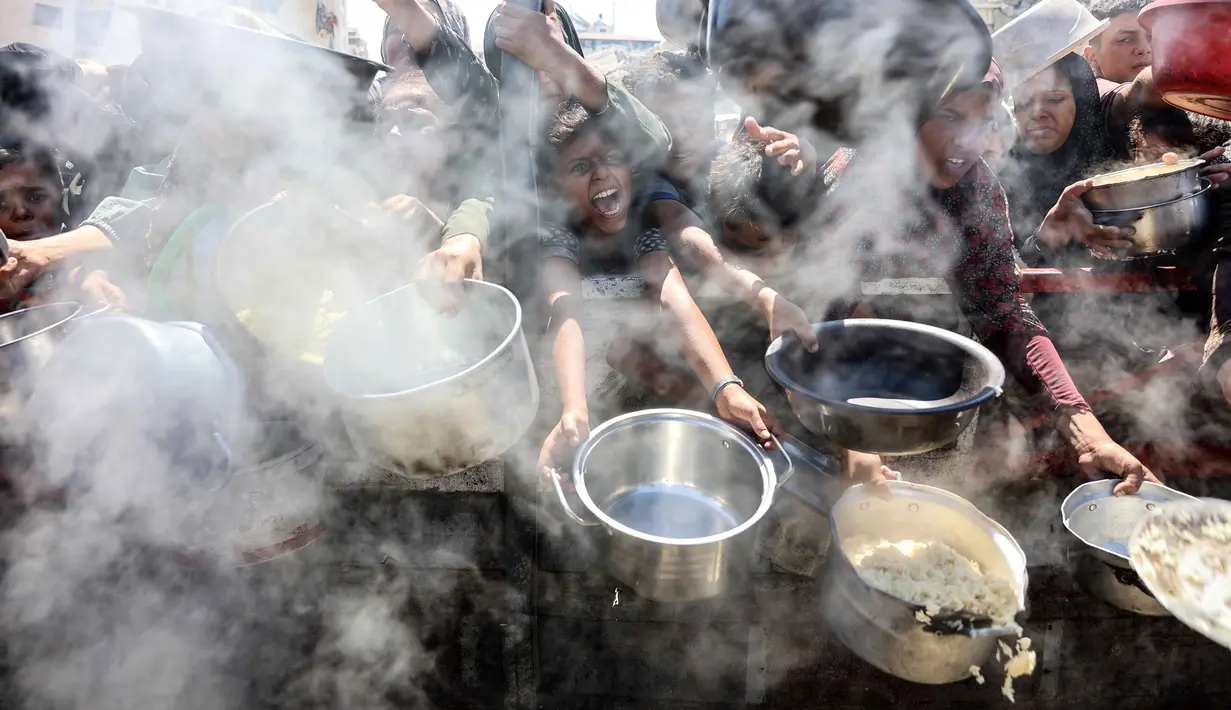 Warga Palestina mengulurkan panci kosong di depan dapur amal untuk menerima makanan matang, di Kota Gaza pada 23 Agustus 2025. (Omar AL-QATTAA/AFP)