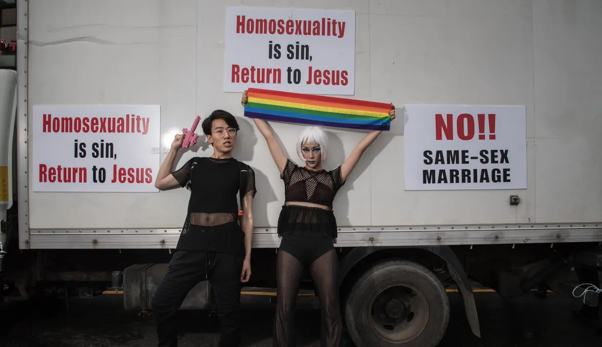 Peserta parade penyuka sesama jenis berfoto dengan poster slogan anti-gay dalam acara 'Gay Pride' di Seoul, Korea Selatan (15/7). Sekitar 10.000 warga korsel turun ke jalan untuk merayakan parade bagi kaum LGBT. (AFP Photo/Ed Jones)