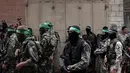 Tentara Hamas mengenakan topeng dan membawa senjata berjaga saat iring-iringan jenazah rekan mereka yang tewas di Deir el-Balah, Jalur Gaza (6/5). (AP/Khalil Hamra)