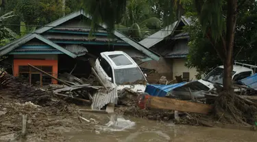Kendaraan hanyut oleh banjir bandang di sebelah rumah-rumah di desa Radda di Kabupaten Luwu Utara, Sulawesi Selatan (14/7/2020). Hujan lebat yang mengakibatkan tiga sungai meluap telah menyapu rumah-rumah, kendaraan dan berbagai fasilitas umum di enam kecamatan di Kabupaten Luwu Utara. (AFP/Aryanto)