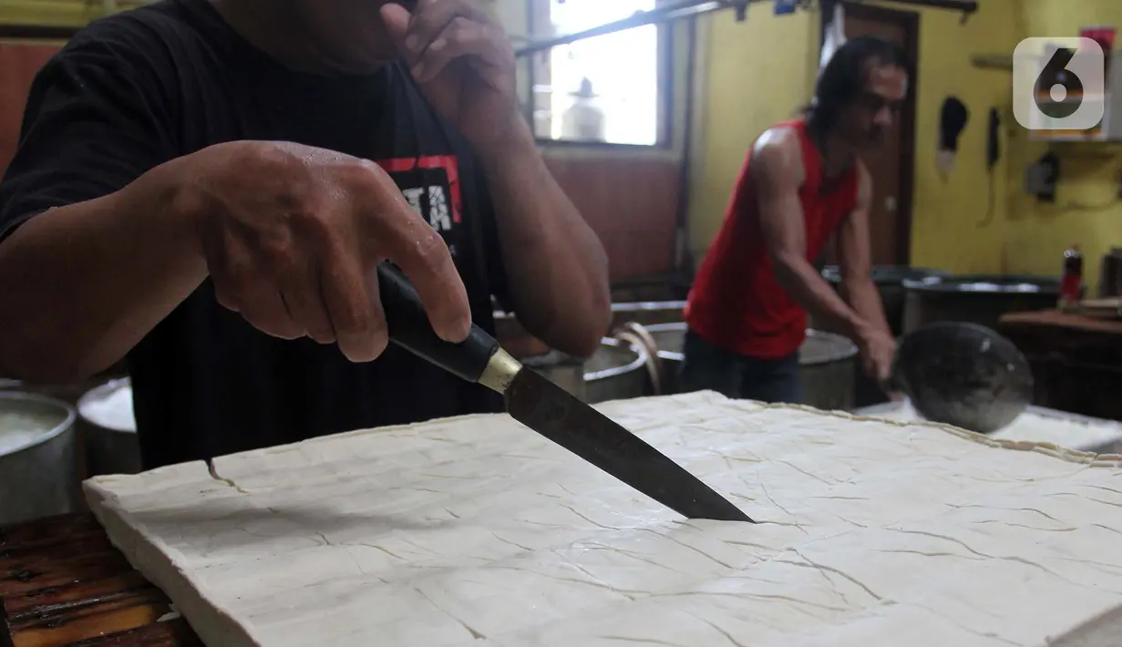 Pekerja menyelesaikan pembuatan tahu di kawasan Pondok Cabe Udik, Tangerang Selatan, Banten, Selasa (15/2/2022). Kenaikan harga kedelai menyebabkan sejumlah pelaku industri tahu dan tempe mengurangi produksinya hingga 50 persen. (merdeka.com/Arie Basuki)