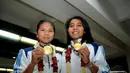 Pebulutangkis ganda putri, Greysia Polii/Nitya Krishinda, memamerkan medali emas Asian Games 2014 sesaat setelah tiba di Bandara Soekarno-Hatta, Selasa (30/9/2014). (Liputan6.com/Helmi Fithriansyah)