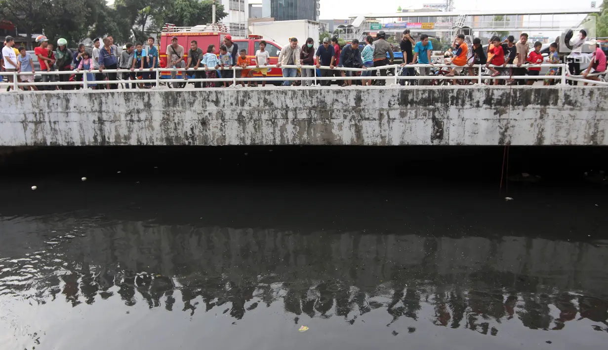 Warga melihat petugas melakukan pencarian buaya di Kali Grogol, Jakarta Barat, Jumat (29/6). Pencarian buaya sempat membuahkan hasil pada hari ketiga, namun kondisi teknis lapangan membuat predator itu kembali lepas. (Liputan6.com/Arya Manggala)