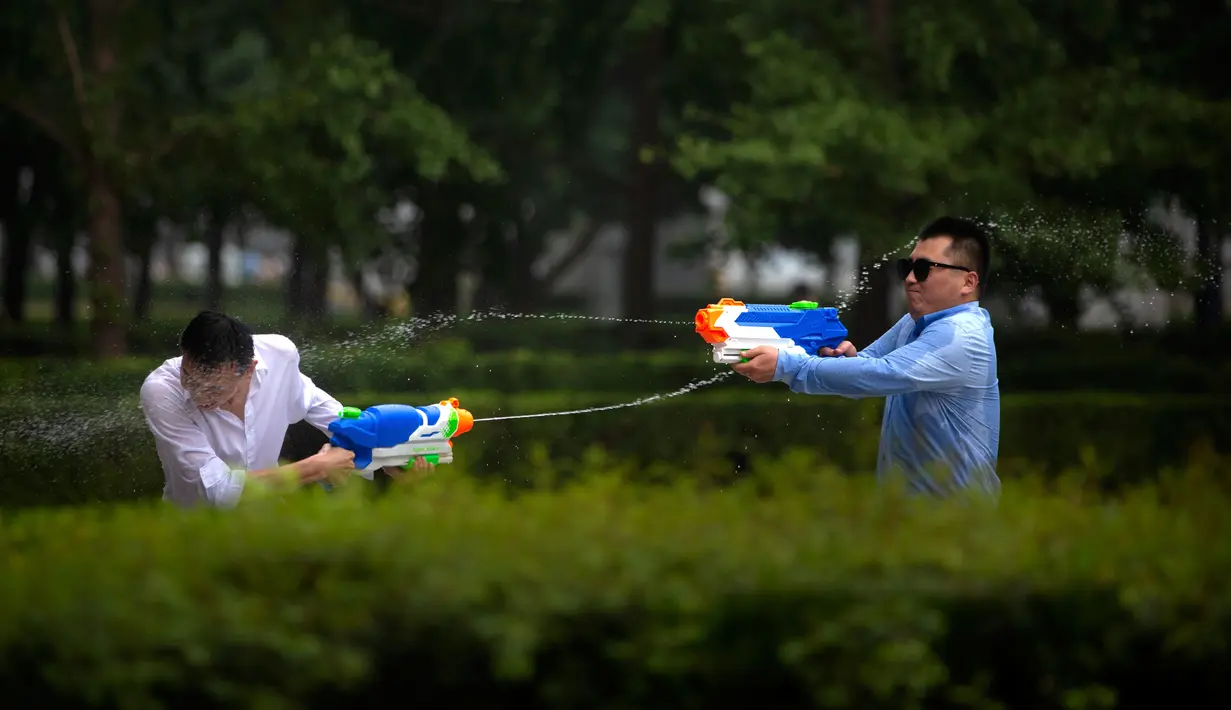 Tiga pekerja kantor bermain semprot-semprotan air di luar kantor, Beijing, (13/7). Karyawan di China terkadang menghabiskan waktu berjam-jam di tempat kerja dan beralih bermain dengan ide kreatif untuk menghilangkan stres. (AP Photo/Mark Schiefelbein)
