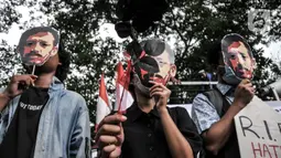 Aktivis yang tergabung dalam Komite Aksi Solidaritas untuk Munir (KASUM) mengenakan topeng berwajah Munir Said Thalib saat memperingati 18 tahun kasus kematian Munir di depan Kantor Komnas HAM, Jakarta, Rabu (7/9/2022). Dalam aksinya, aktivis mengenakan topeng dan membawa replika peti mati serta papan nisan sebagai bentuk protes atas lambannya Komnas HAM dalam menetapkan kasus Munir sebagai Pelanggaran HAM Berat dan mendesak segera mengusut tuntas kasus pembunuhan yang terjadi pada 7 September 2004 itu. (merdeka.com/Iqbal S. Nugroho)
