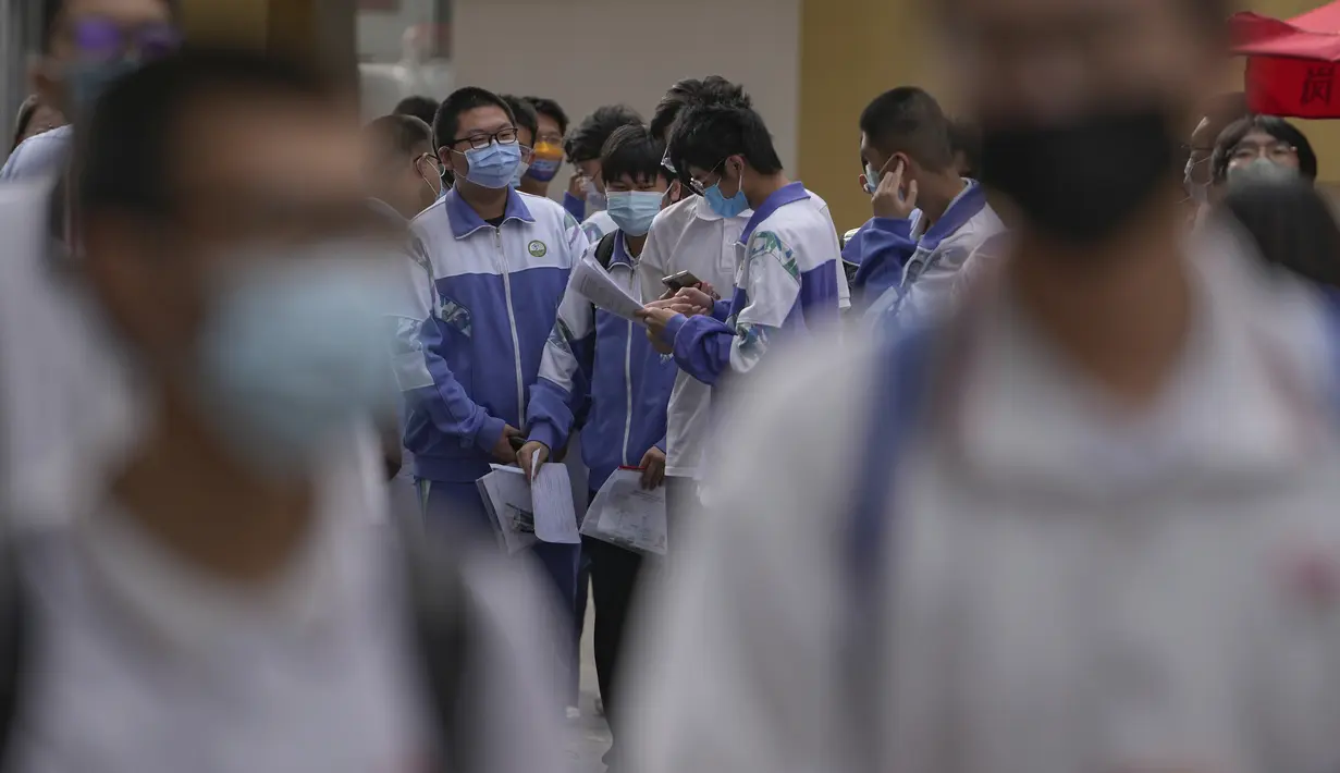 Siswa bermasker melihat kertas teks di luar sekolah sebelum hari pertama ujian masuk perguruan tinggi nasional China, di Beijing, Selasa (7/6/2022). Ujian selama dua hari yang dikenal sebagai gaokao itu merupakan penentu utama bisa diterimanya para pelajar di perguruan-perguruan tinggi bergengsi di negara itu. (AP Photo/Andy Wong)