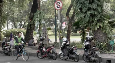 Pengendara sepeda melintas di samping deretan sepeda motor yang terparkir di sekitar Taman Suropati, Jakarta, Selasa (28/8). Meski terpampang rambu larangan parkir dan berhenti, pengendara tetap parkir di sekitar taman. (Liputan6.com/Immanuel Antonius)