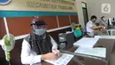 Petugas Dinas Kependudukan dan Catatan Sipil menggunakan pelindung wajah saat mengurus KTP-el di Kecamatan Pamulang, Tangerang Selatan, Rabu (3/6/2020). Sejumlah kantor pelayanan pemerintah melaksanakan protokol kesehatan yang ketat untuk memutus rantai penyebaran covid-19. (merdeka.com/Arie Basuki)