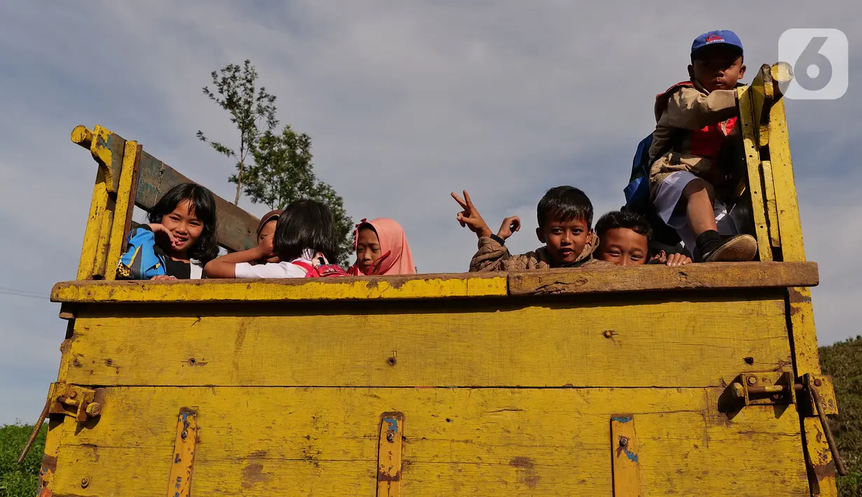 Sejumlah siswa menumpang truk di kawasan Cikoneng, Bogor, Selasa (30/3/2021). Untuk menuju sekolahnya di SDN Cikoneng, sebagian siswa harus menumpang truk, jalan kaki dan membawa kendaraan pribadi karena akses jalan yang sulit di daerah perbukitan perkebunan teh. (Liputan6.com/Herman Zakharia)