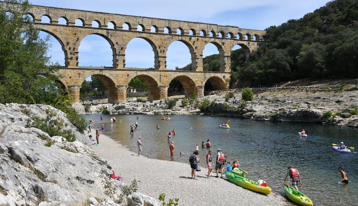 Wisatawan bermain kayak di dekat Pont du Gard atau Jembatan Gard di Vers-Pont-du-Gard, Prancis, Rabu (21/8/2019). Pont du Gard dibangun oleh Marcus Vipsanius Agrippa menantu dari Caesar Augustus. (Pascal GUYOT/AFP)