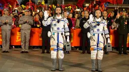 Astronot Tiongkok, Jing Haipeng (kanan), dan Chen Dong, melambaikan tangan sebelum berangkat dengan pesawat ruang angkasa Shenzhou 11 di Jiuquan Satellite Launch Center, Tiongkok, (17/10). (China Daily/via REUTERS)