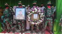 Prajurit TNI memegang foto dan karangan bunga di depan peti jenazah Pelda Anumerta Rama Wahyudi. (Liputan6.com/M Syukur)