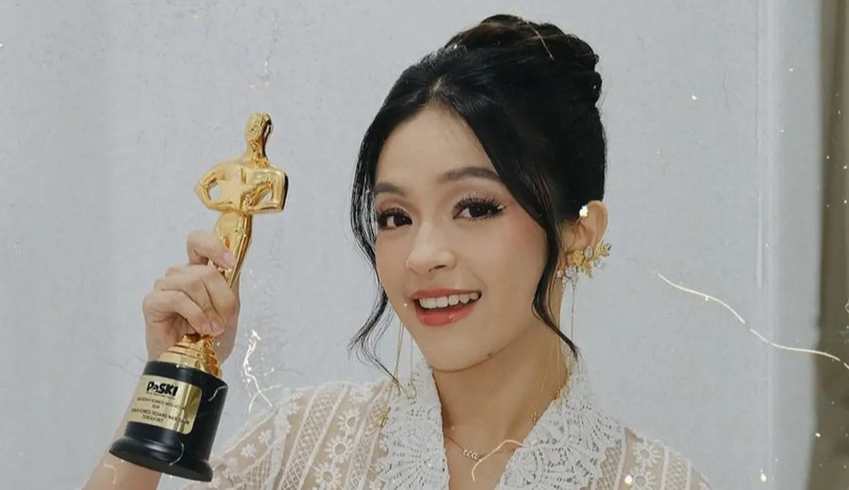 <p>Wajahnya dipoles dengan blush tipis coral senada dengan warna lipstik glossynya. Riasan mata dibuat soft dengan shimmer dan garis putih di kelopak mata dan sedikit eyeliner wings. Rambutnya ditata sanggul modern tanpa hiasan dengan poni membingkai wajah. [elsaajapasal]</p>