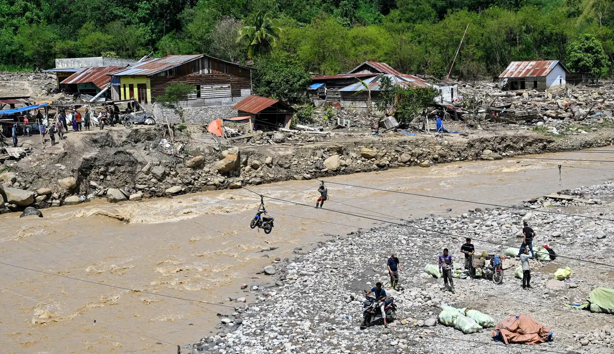 Meski berbahaya, tali sling menjadi satu-satunya cara agar mobilitas warga Aceh Tengah tetap berjalan. Tampak dalam foto, warga menggunakan tali untuk menyeberangi sungai setelah banjir bandang yang menghancurkan desa-desa di sekitarnya di Ketol, provinsi Aceh, pada Selasa 6 Januari 2026. (CHAIDEER MAHYUDDIN/AFP)