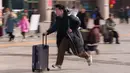 Seorang pria berlari sambil menyeret koper di stasiun kereta api saat orang-orang pulang kampung selama liburan Tahun Baru Imlek di Beijing, China, Selasa 10 Februari 2026. Gelombang migrasi penduduk tahunan terbesar China telah dimulai. (AP Photo/Vincent Thian)