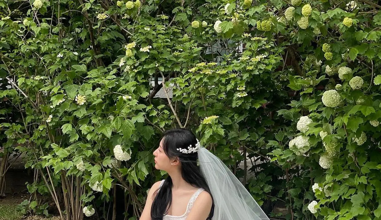 Kim Ji Won tampil super cantik mengenakan gaun pengantin putih dan veilnya yang menyempurnakan keseluruhan penampilannya di drama Queen of Tears. Di sini, Kim Ji Won membiarkan rambut hitam panjangnya tergerai, serasi dengan gaun pengantin tanpa lengan yang dikenakannya. [Foto: Instagram/geewonii]