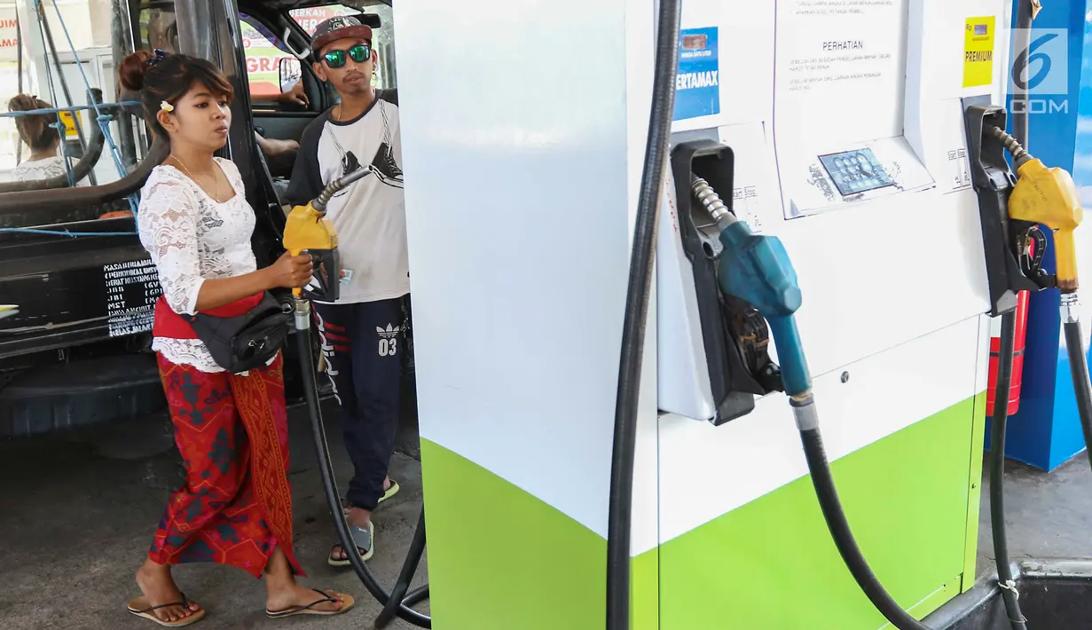 Petugas dengan pakaian adat mengisi bahan bakar minyak (BBM) ke sebuah mobil di SPBU, Bali, Rabu (10/10). Petugas SPBU mengenakan pakaian adat Bali untuk menyambut pertemuan tahunan IMF dan Bank Dunia. (Liputan6.com/Angga Yuniar)