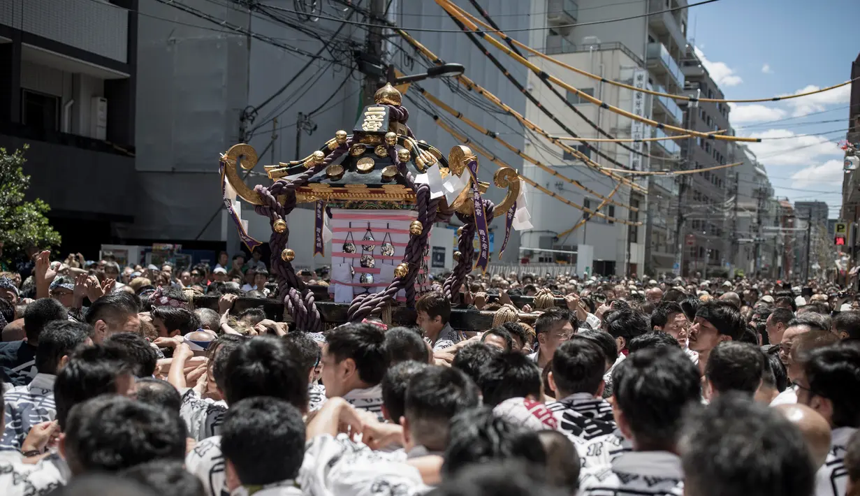 Peserta membawa kuil portabel atau "Mikoshi" pada Festival Sanja Matsuri di luar kuil Sensoji, distrik Asakusa, Tokyo, Minggu (20/5). Sanja Matsuri ini adalah salah satu festival agama Shinto terbesar yang diadakan di Tokyo. (AFP/Behrouz MEHRI)