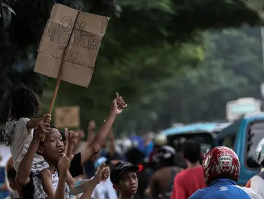 Sejumlah anak membawa spanduk pesan Om Telolet Om agar pengemudi bus membunyikan klakson di Jalan Raya Bogor, Jakarta, Sabtu (24/12). Libur sekolah dimanfaatkan anak-anak untuk berburu bus yang membunyikan klakson telolet. (Liputan6.com/Faizal Fanani)