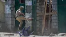 Polisi India menendang gerbang sebuah perguruan tinggi di Srinagar, Kashmir yang dikuasai India, (23/5). Bentrokan telah meningkat setelah tentara menggerebek sebuah perguruan tinggi di kota selatan Pulwama bulan lalu. (AP Photo/Dar Yasin)