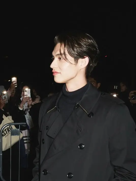 Duduk di front row, Bright memadukan turtleneck dengan celana panjang dan trenchcoat. @gmmtv.