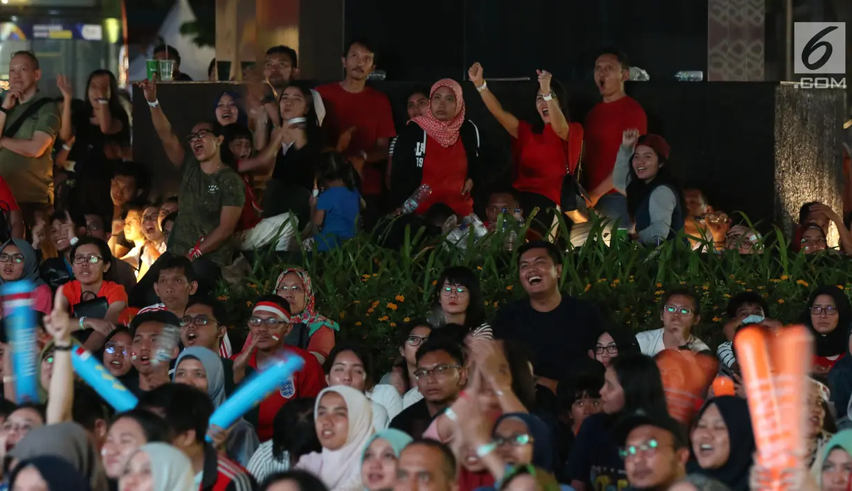 Suporter tim bulutangkis Indonesia bersorak saat menyaksikan siaran langsung laga perempat final dan 16 besar bulutangkis Asian Games 2018 melalui layar lebar di kawasan kompleks GBK, Jakarta, Sabtu (25/8). (Liputan6.com/Helmi Fithriansyah)
