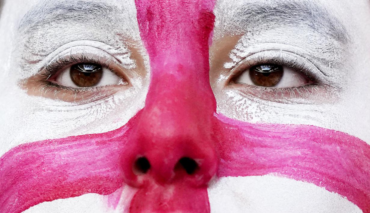 Suporter mewarnai mukanya dengan bendera nasional Inggris saat menyaksikan pertandingan melawan Denmark pada laga semifinal Euro 2020 di Stadion Wembley, Kamis (8/7/2021). (Foto:AFP/Frank Augstein,Pool)