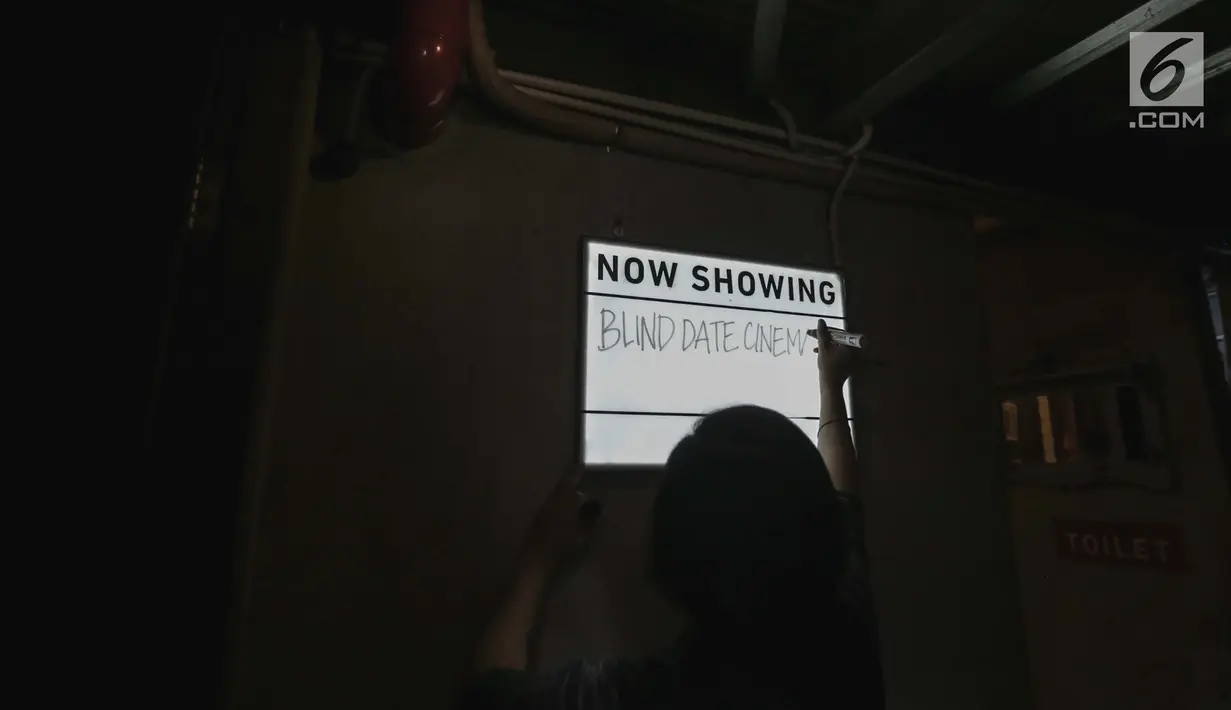 Seorang petugas Bioskop Tunantra menulis di papan pengumuman jelang pemutaran film di Bioskop Bisik di Pavilliun 28, Jakarta, Minggu (14/1). Hal ini membuat menonton bioskop bukan menjadi hal mustahil lagi bagi tunanetra. (Liputan6.com/Faizal Fanani)