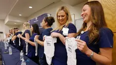 Paige Packard dan Allison Thompson memegang pakaian bayi ketika konferensi pers bersama 16 suster di bagian gawat darurat sebuah rumah sakit di Mesa, Arizona yang sedang hamil pada periode yang relatif bersamaan, 17 Agustus 2018. (AP/Ross D. Franklin)