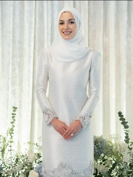 Baju kurung satin warna putih dengan aksen bordiran di tepian juga tak kalah elegan. Padukan dengan hijab warna senada. [@tehfirdaus]