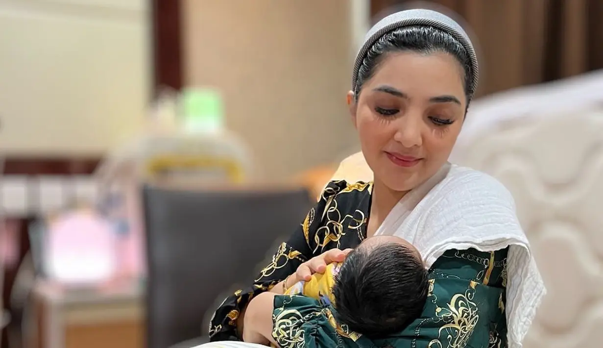 Aurel baru saja melahirkan putrinya, yang juga merupakan cucu pertama dari Ashanty. Di sini terlihat pancaran kebahagiaan Ashanty ketika menggendong sang cucu mengenakan dress bermotif rantai dengan nuansa hijau tua. Ia tampil dengan makeup natural dan mengenakan bando untuk menata rapi rambutnya.