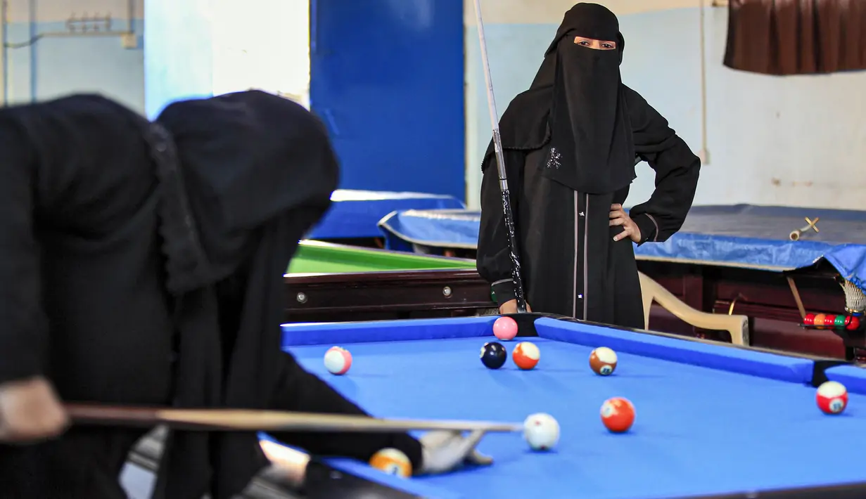 Seorang wanita melihat lawannya membidik bola saat mengikuti kejuaraan biliar lokal di sebuah gedung olahraga di ibu kota  Sanaa, Yaman  (16/12/2019).  (AFP/Mohammed Huwais)