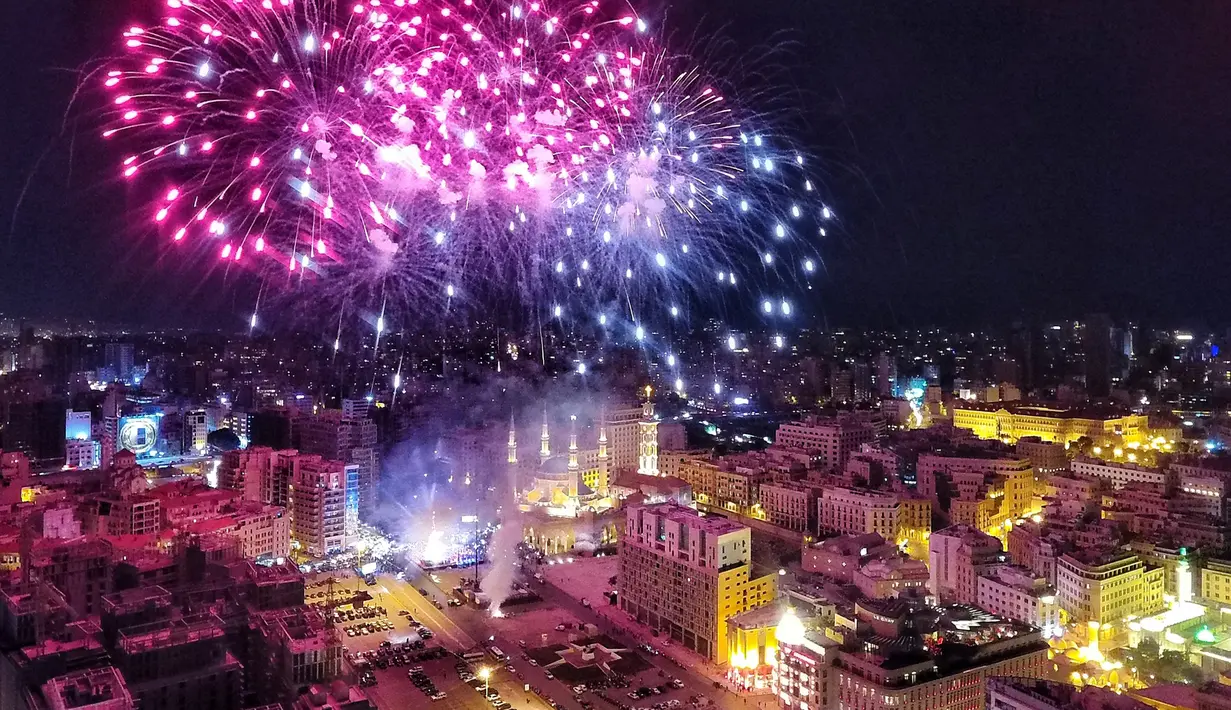 Kembang api menghiasi langit diatas Masjid Mohammad al-Amin saat acara peresmian menyalakan lampu pohon natal di Beirut, Lebanon (10/12). Menyambut datangnya natal, warga Beirut merayakan peresmian pohon natal. (AFP Photo/Stringer)