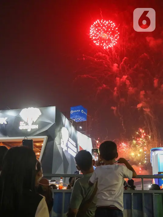Pengunjung mengambil gambar pesta kembang api di langit saat Jakarta Fair ke-53 atau Pekan Raya Jakarta (PRJ) di JiExpo Kemayoran, Jakarta Pusat, Selasa (21/6/2022) malam. Pesta kembang api menggelegar di kawasan PRJ bertepatan dengan HUT Jakarta yang jatuh pada besok, 22 Juni 2022. (Liputan6.com/Herman Zakharia)