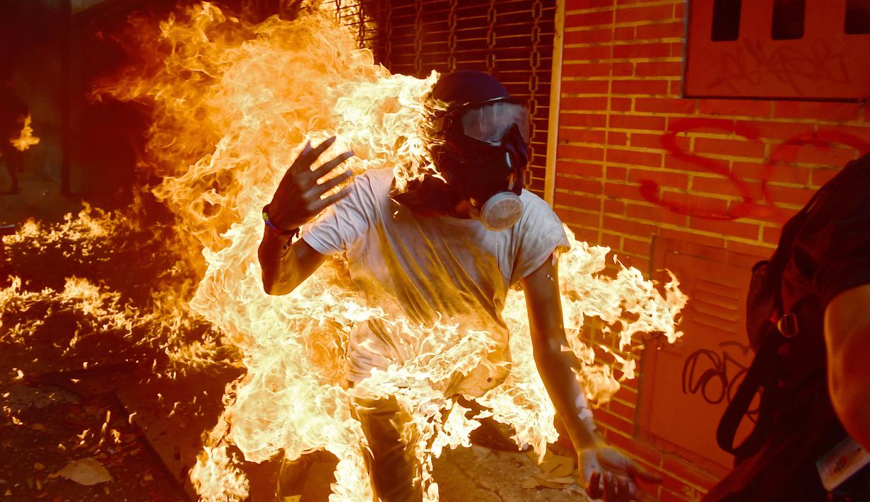 Seorang demonstran terbakar saat unjuk rasa menentang Presiden Venezuela, Nicolas Maduro di Caracas, Rabu (3/5). Pria tersebut tersulut api dari ledakan tangki sepeda motor milik polisi saat unjuk rasa yang diwarnai bentrokan. (RONALDO SCHEMIDT / AFP)