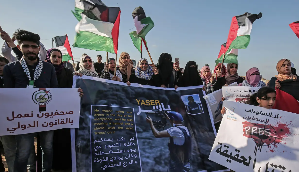 <p>Sejumlah warga Palestina membawa poster saat menggelar aksi protes terkait pembunuhan wartawan Yasser Murtaja di dekat perbatasan Israel-Gaza, Palestina (8/4). (AFP Photo/Said Khatib)</p>