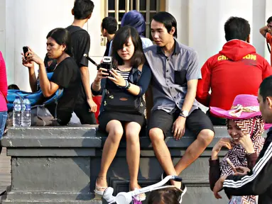 Remaja berfoto bersama saat berwisata di Kota Tua, Jakarta, Minggu (8/5). Keunikan bangunan tua di kawasan tersebut menjadi daya tarik tersendiri bagi warga untuk melakukan foto bersama atau selfie. (Liputan6.com/Immanuel Antonius)