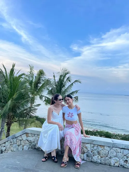 Saat bermain ke pantai, Enzy memilih dress warna putih berpotongan a-line. Penampilannya itu disempurnakan dengan kacamata hitam.