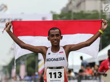 Pelari Indonesia Agus Prayogo membawa Bendera Merah Putih usai melakukan trek maraton SEA Games XXIX di di Putrajaya, Kuala Lumpur, Malaysia, Sabtu (19/8). Agus berhasil meraih medali perak nomor lari marathon cabang atletik. (Liputan6.com/Faizal Fanani)